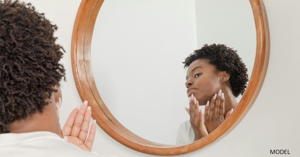 Woman applying lotion in mirror