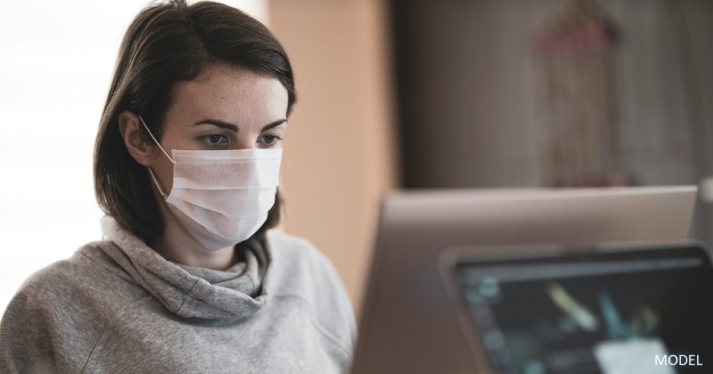 Woman using a computer wearing a mask